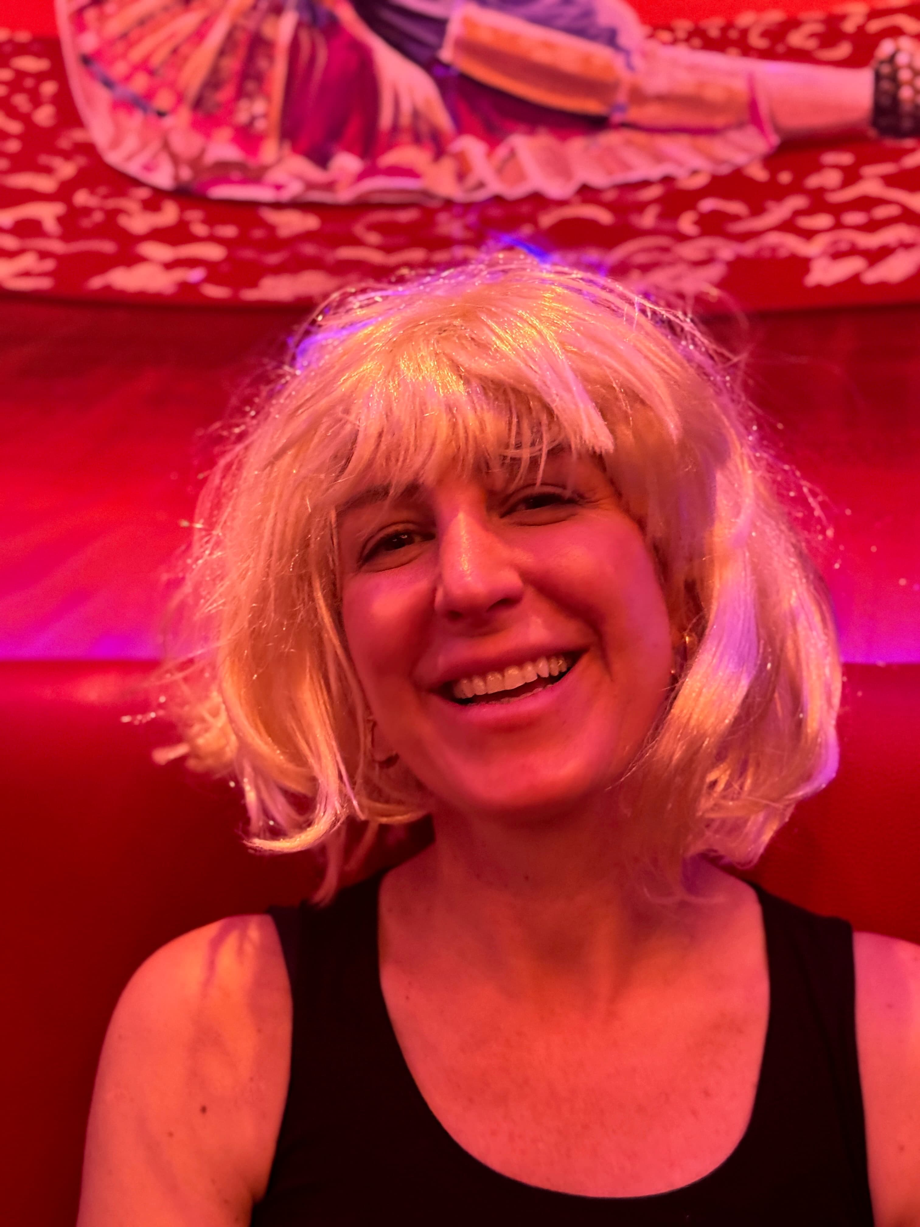 Smiling guest in a short blonde wig seated at a party