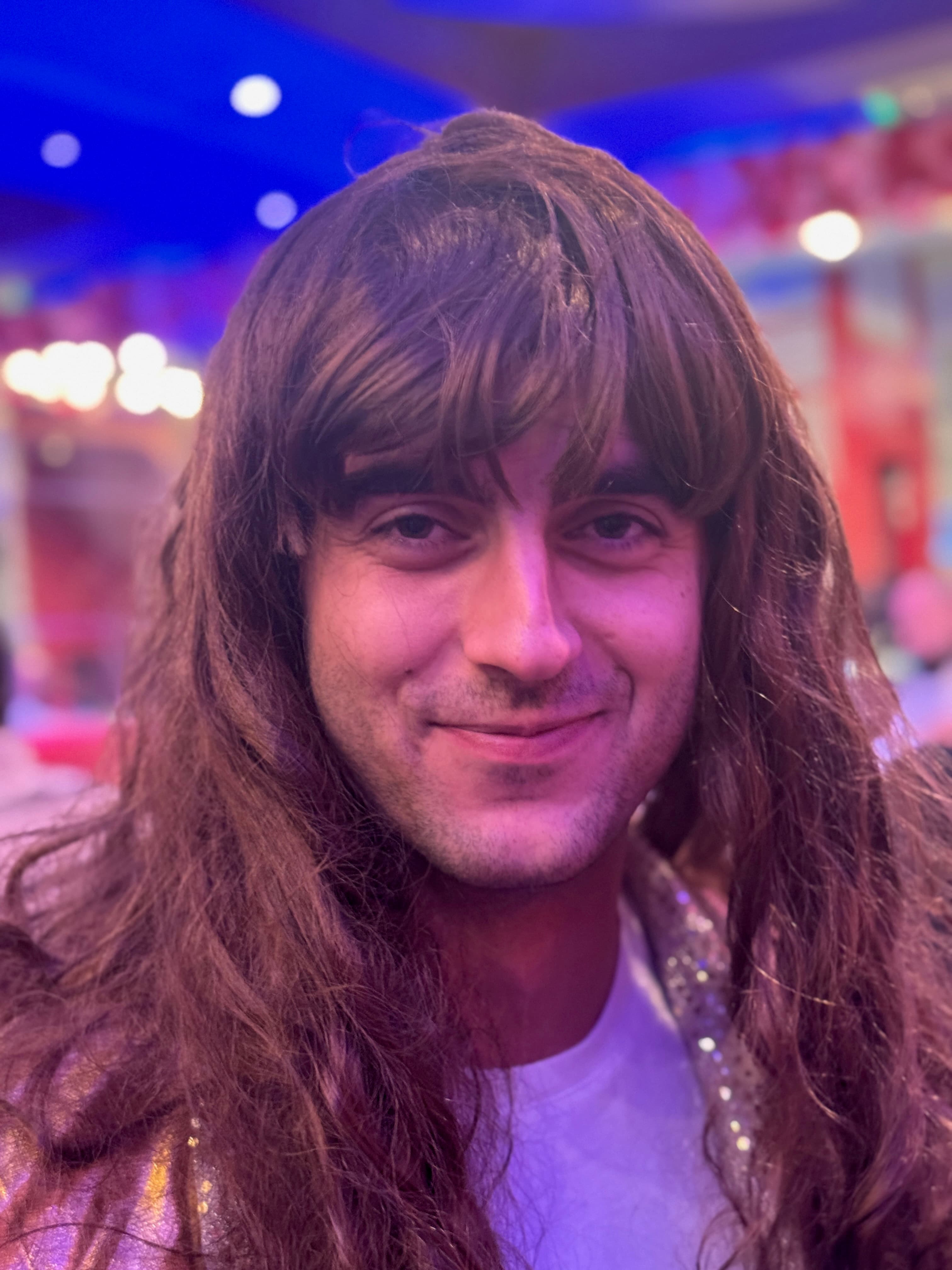 Guest in wig and eveningwear smiling in a saturated party portrait