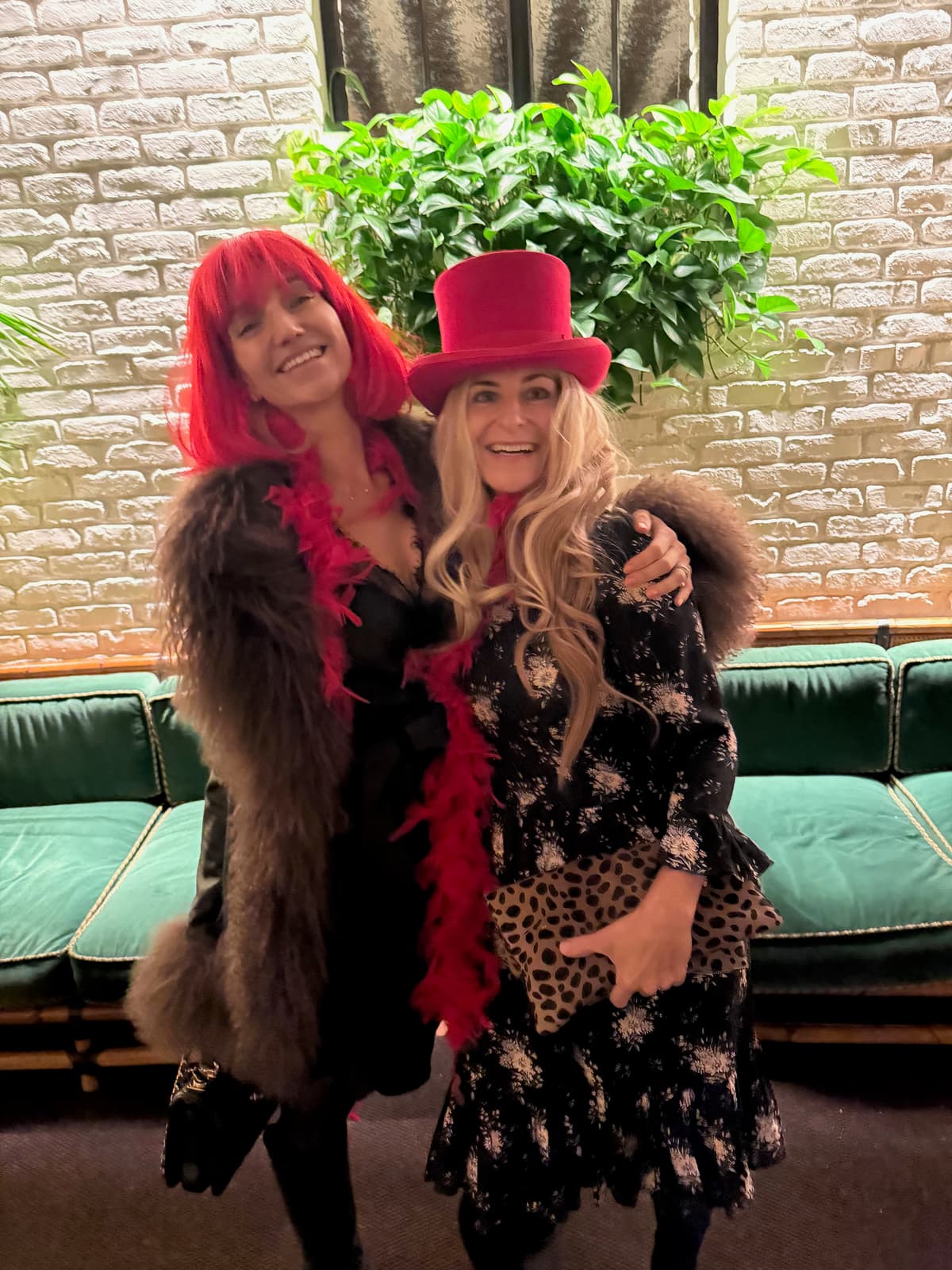 Two costumed friends posing with a feather boa and pink top hat