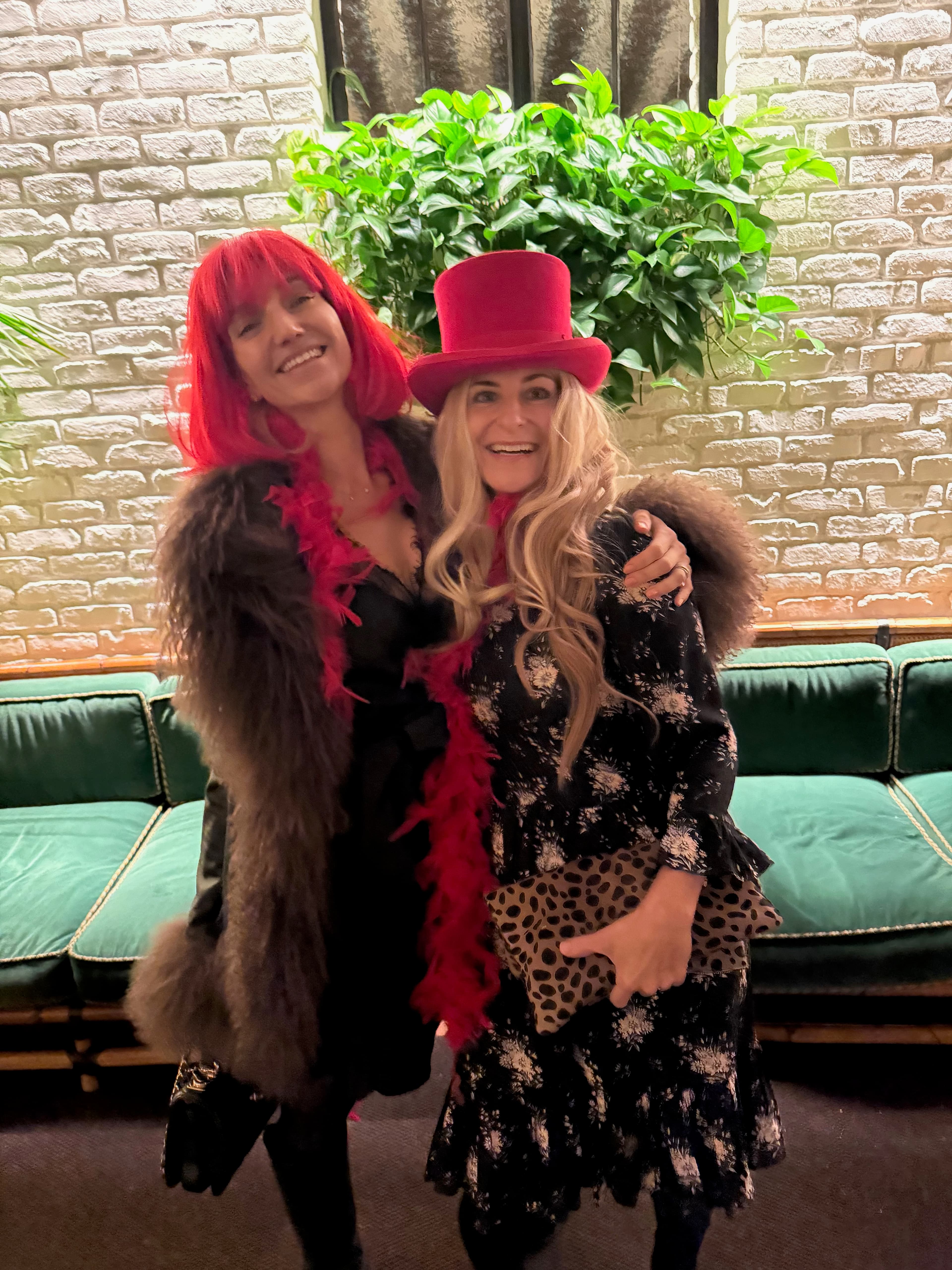 Two costumed friends posing with a feather boa and pink top hat