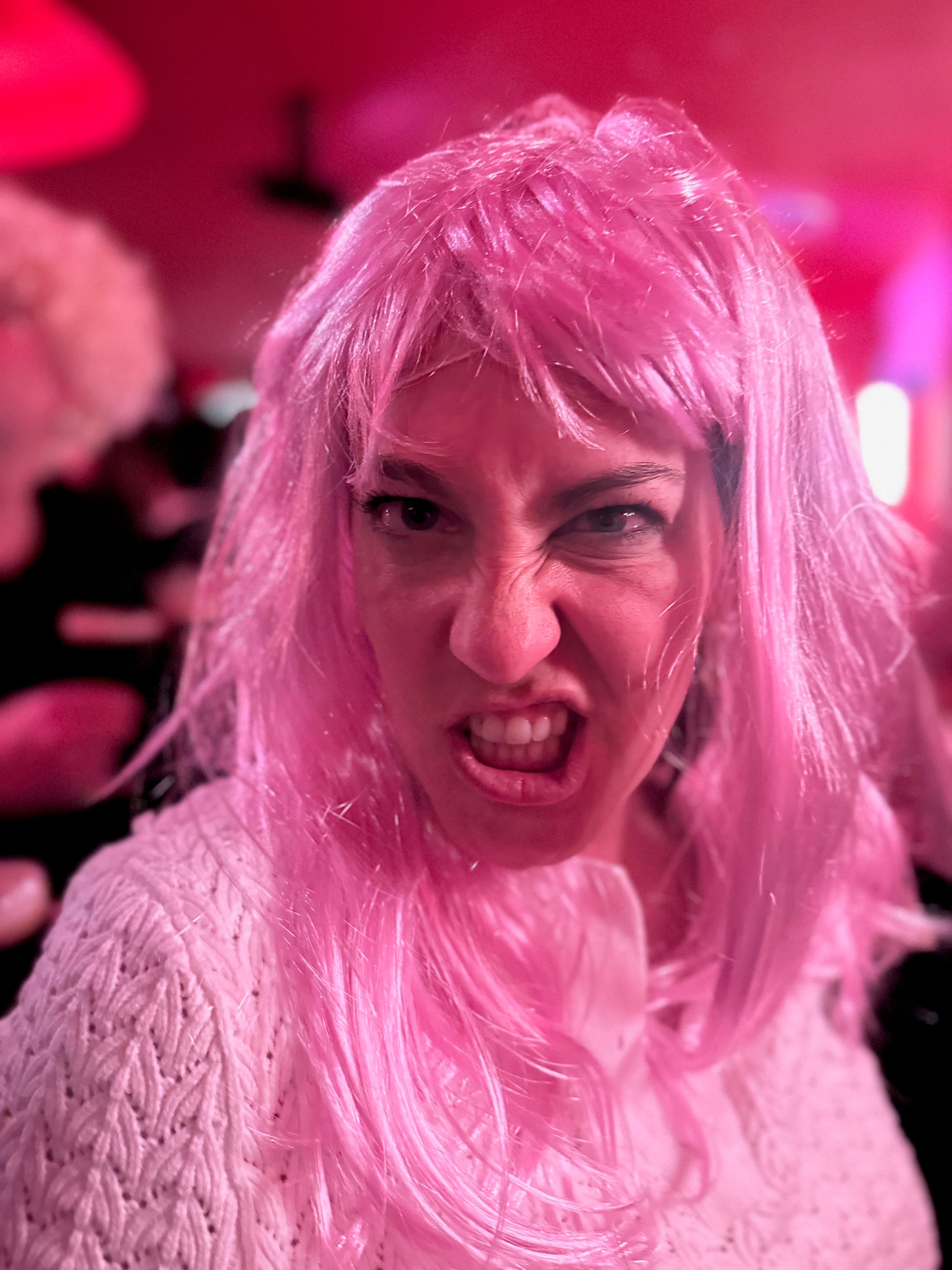 Flash-lit close-up of a guest in a bright wig at the party