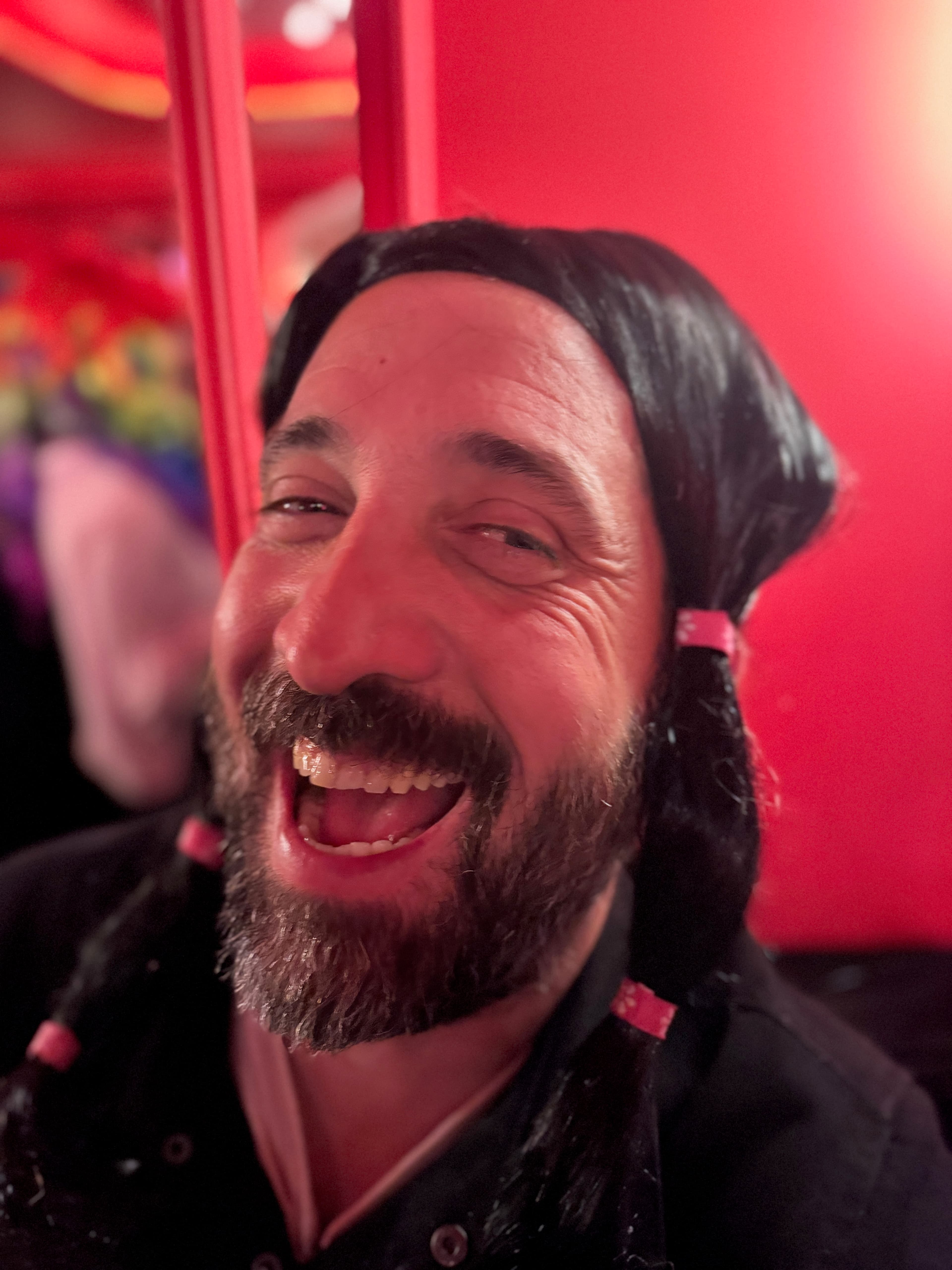 Party portrait with wig, drink, and strong red nightlife lighting